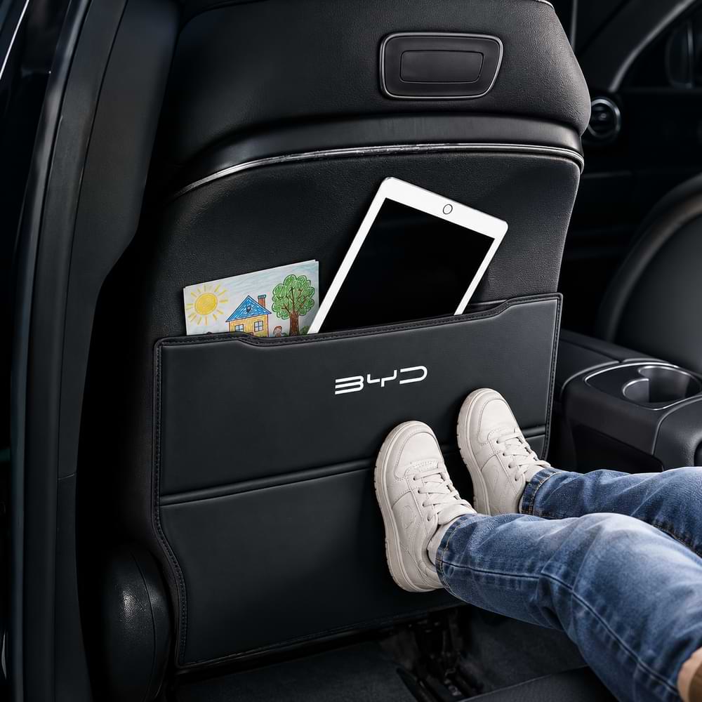 Car seat with a BYD pocket organizer holding a tablet and a card, with a person's legs visible.