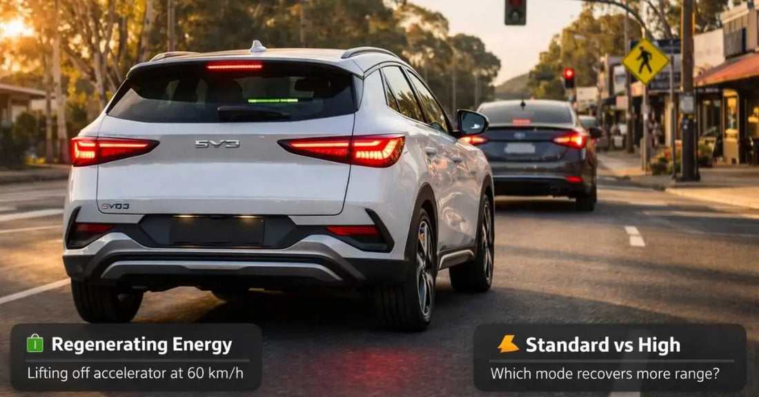 White BYD Atto 3 decelerating at a suburban traffic light with brake lights on showing regenerative braking energy recovery in real world driving