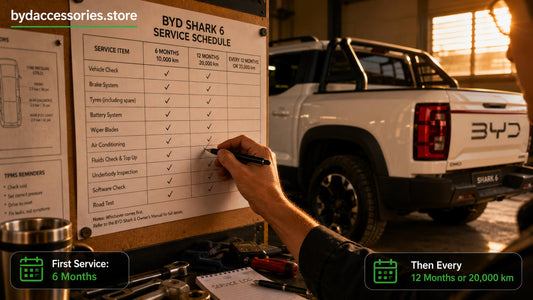 Printed BYD Shark 6 service schedule chart being ticked off beside the ute in a home workshop
