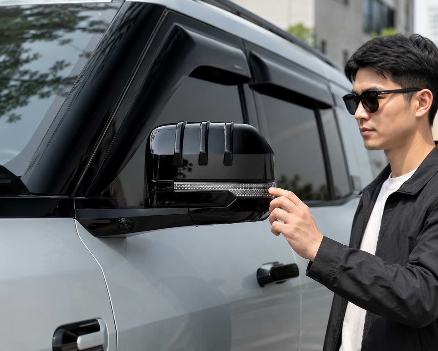 Model inspecting the BYD Leopard 8 2024-2025 rearview mirror fitted with a gloss black ABS mirror protection cover.