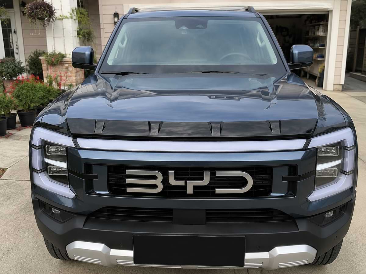 BYD Shark 6 parked in front of a home with gloss black hood shield deflector installed